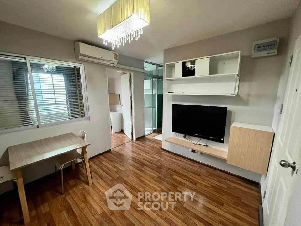 Modern living room with wooden flooring, TV, and dining area in a cozy apartment.