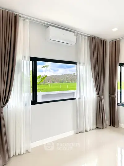 Bright living room with large windows and scenic view of green fields.