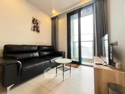 Modern living room with black leather sofa and balcony view, ideal for urban living.