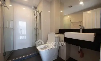 Modern bathroom with glass shower and sleek fixtures in contemporary apartment.