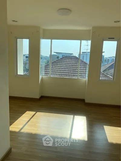 Bright room with large windows offering a scenic view of rooftops and city skyline, perfect for a cozy living space.