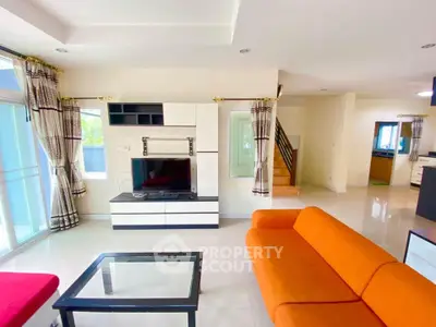 Spacious modern living room with vibrant orange sofa and sleek entertainment unit