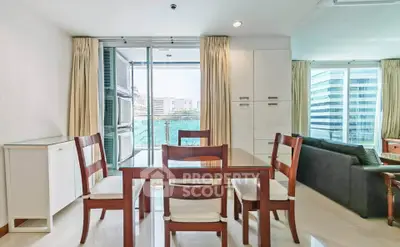 Spacious modern living room with glass dining table and city view balcony in high-rise apartment.