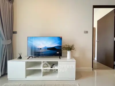 Modern living room with sleek TV stand and open door, showcasing minimalist decor and natural light.