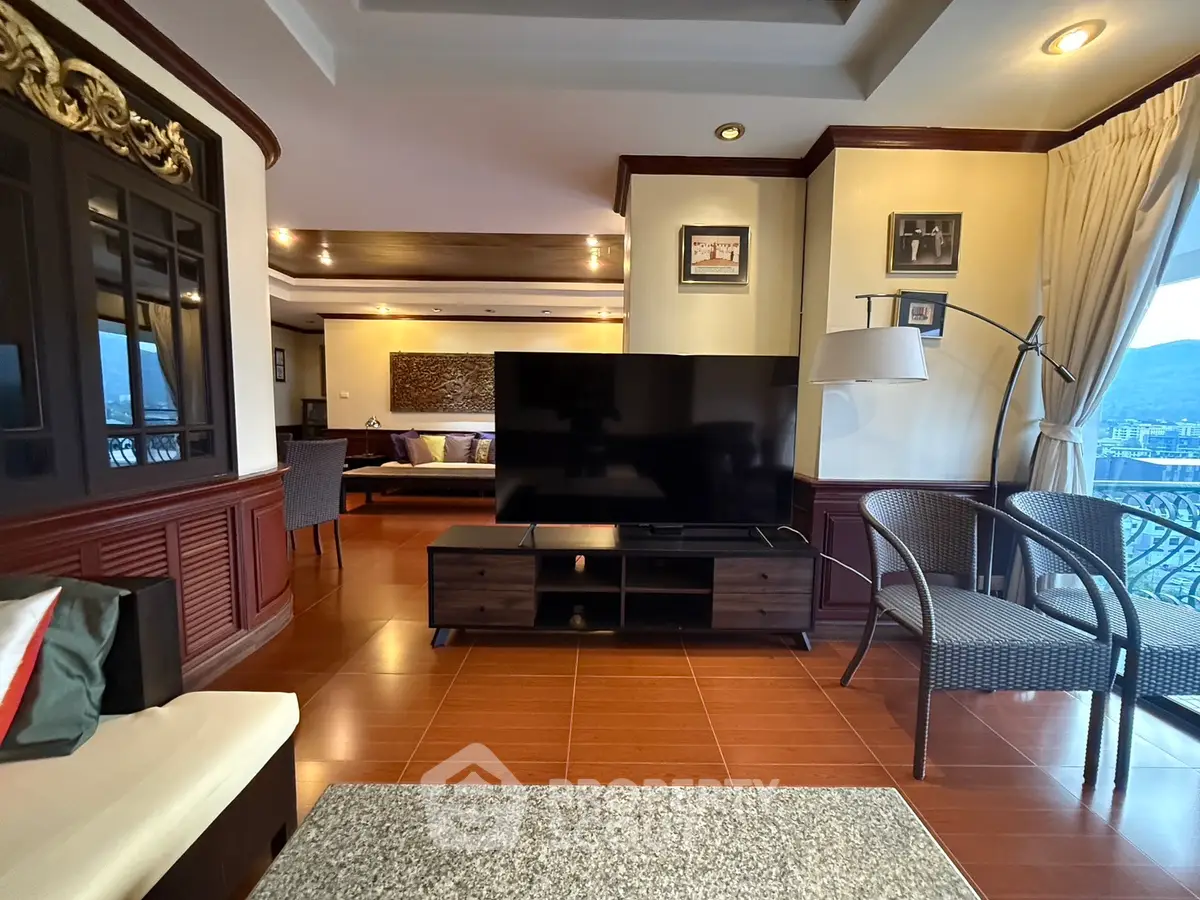 Spacious living room with modern decor and large TV, featuring elegant wooden flooring and mountain views.