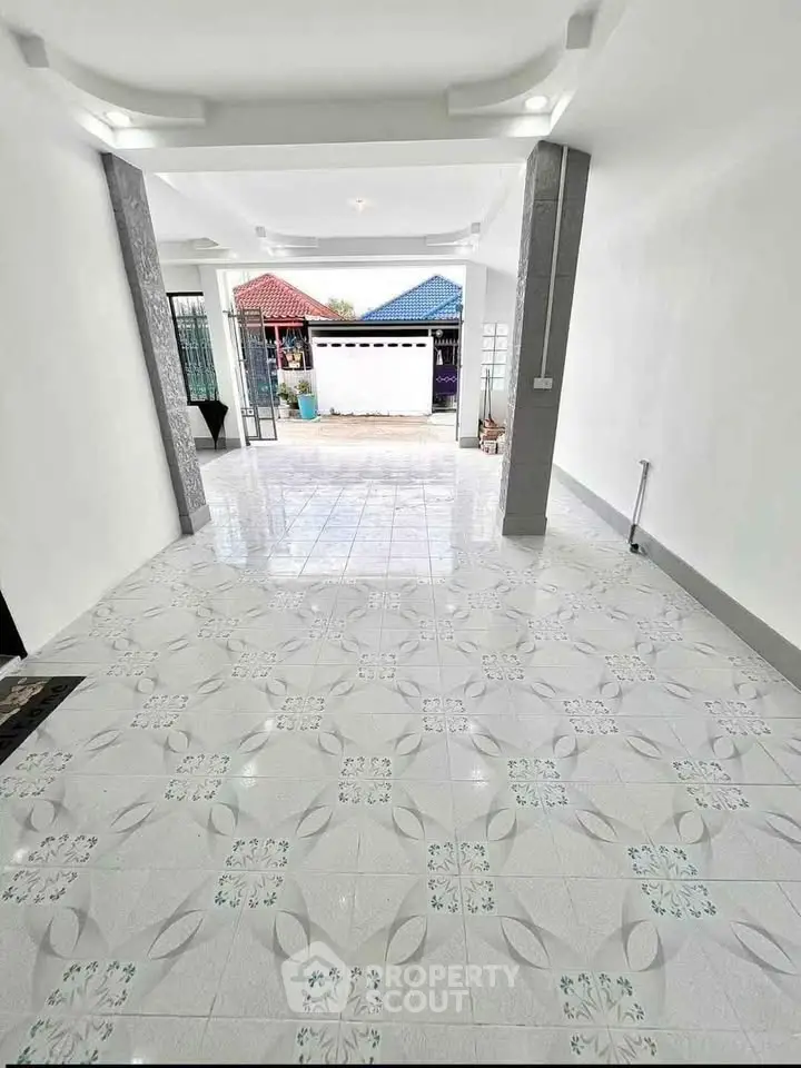 Spacious tiled entrance with modern design leading to a vibrant outdoor view.