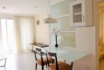 Bright modern dining area with glass table and stylish chairs in open-plan apartment.