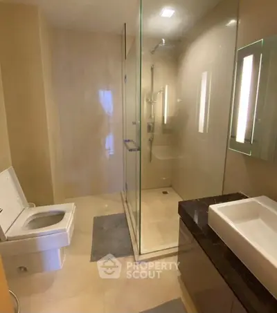 Modern bathroom with glass shower and sleek fixtures in luxury apartment.
