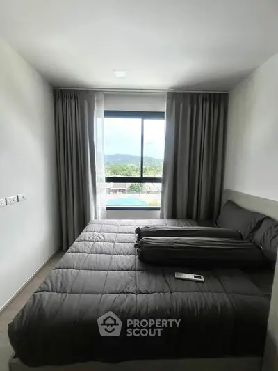 Modern bedroom with large window offering scenic views and cozy bedding.
