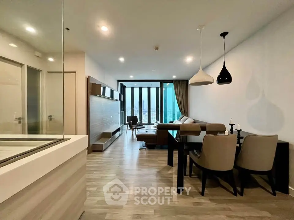 Modern living room with stylish furniture and open layout, featuring large windows and elegant lighting.