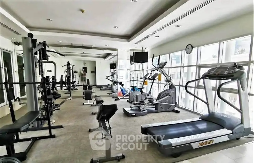 Spacious modern gym with state-of-the-art equipment and large windows for natural light.