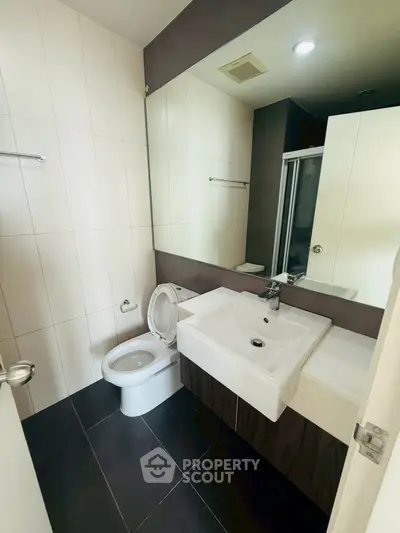 Modern bathroom with sleek fixtures and large mirror in a contemporary apartment.