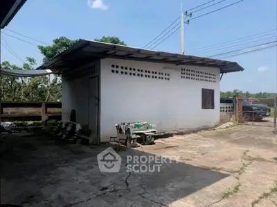 Spacious outdoor area with a small white building, perfect for storage or workshop use.