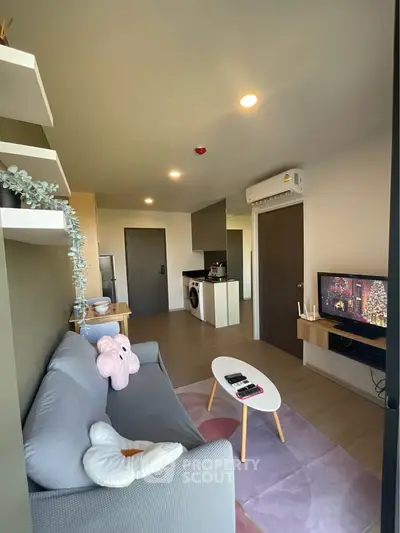 Modern living room with cozy sofa, TV, and open kitchen layout in stylish apartment.