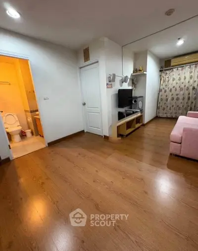 Spacious living room with wooden flooring and adjacent bathroom in modern apartment.
