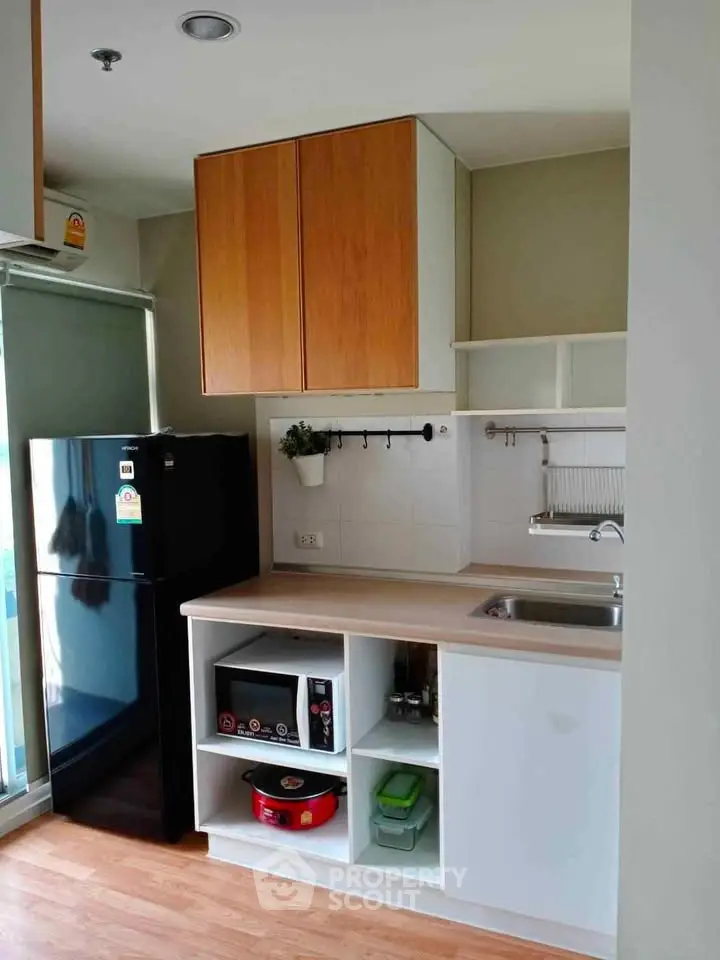 Modern compact kitchen with sleek cabinets and appliances in a cozy apartment.