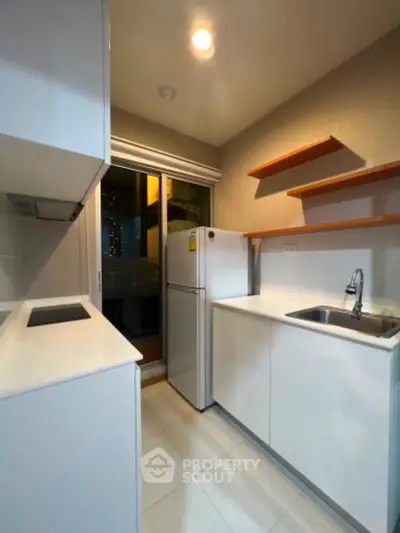 Modern compact kitchen with sleek white cabinets and built-in appliances
