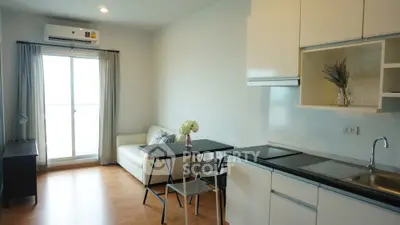 Modern open-layout living room with kitchen, featuring sleek design and natural light.