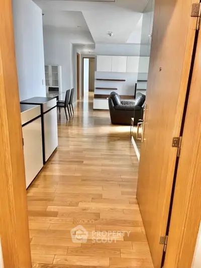 Spacious modern apartment entrance with wooden flooring and stylish furniture.