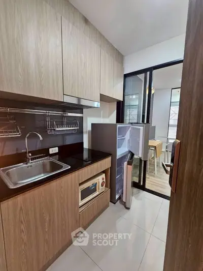 Modern kitchen with sleek wooden cabinets and open fridge in stylish apartment.