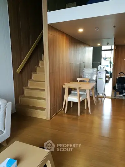 Modern duplex apartment with elegant wooden staircase and sleek furniture, featuring a bright and airy living space with natural light.