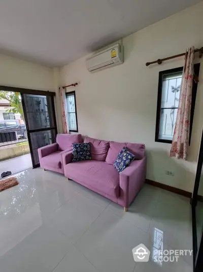 Spacious living room with gleaming tiled floors, large windows, and a comfortable pink sofa set, perfect for family relaxation and social gatherings.