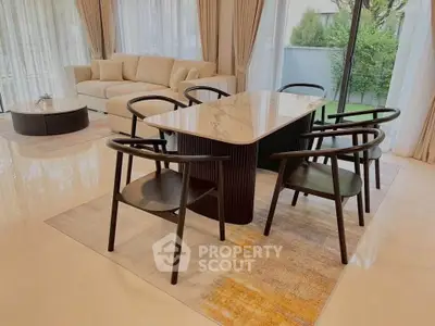 Elegant living room with modern dining set and large windows overlooking garden