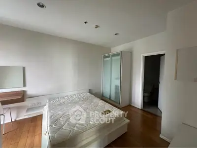 Spacious bedroom with wooden flooring and modern furniture