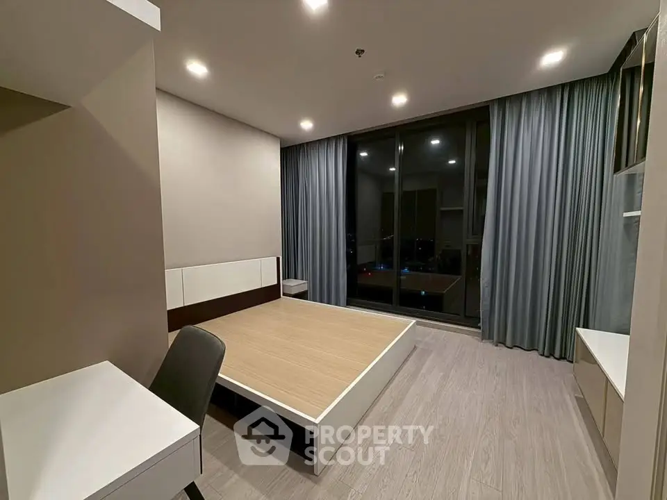 Modern bedroom with sleek design and large window offering city views