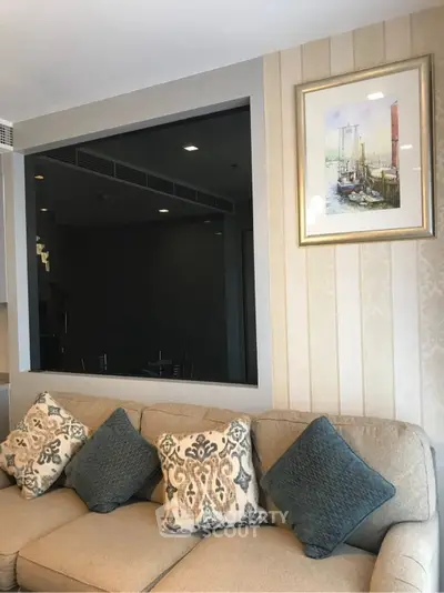 Elegant living room with stylish sofa and decorative pillows, featuring a framed artwork on the wall.