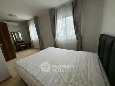 Spacious bedroom with modern decor and large windows for natural light.