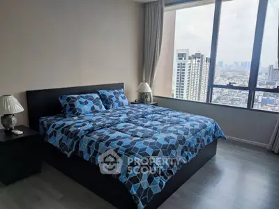 Spacious bedroom with large windows offering panoramic city views, modern furnishings, and ample natural light.