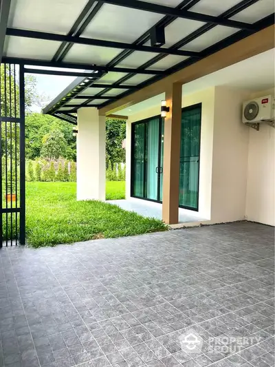 Modern patio with tiled flooring and garden view, featuring sliding glass doors and air conditioning unit.