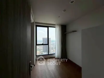 Spacious room with large window offering stunning city views in modern high-rise building.