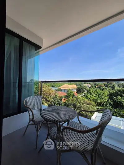 Charming balcony with outdoor seating and scenic view of lush greenery.