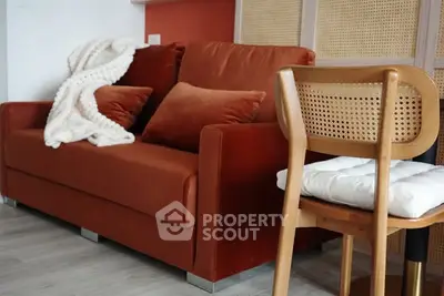 Cozy living room with plush orange sofa and stylish wooden chair