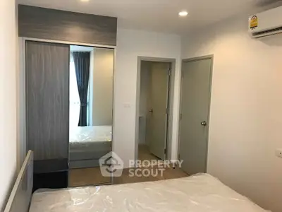 Modern bedroom with mirrored wardrobe and air conditioning in a stylish apartment.