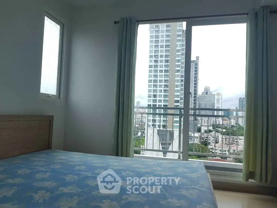 Modern bedroom with city view from large window, featuring a simple bed setup.