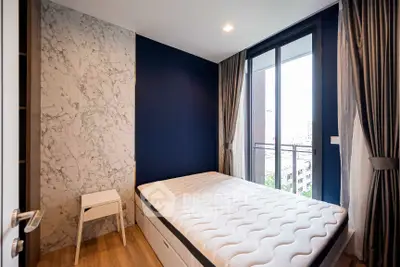 Modern bedroom with large window and city view, featuring stylish decor and natural light.