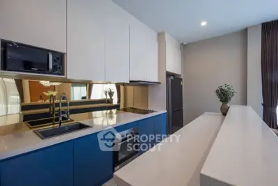 Modern kitchen with sleek blue cabinets and built-in appliances, featuring a stylish open layout.