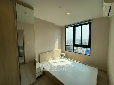 Modern bedroom with large window offering city views, featuring minimalist design and ample natural light.