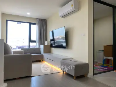 Modern living room with sleek furniture and large TV, featuring natural light and cozy ambiance.