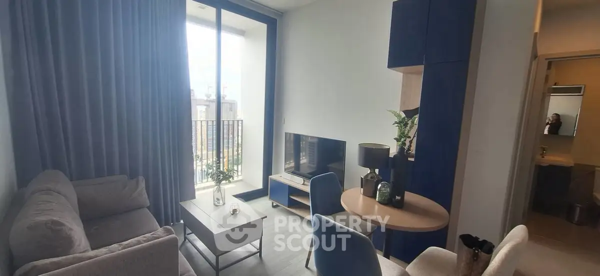 Modern living room with balcony view, stylish furniture, and natural light in a contemporary apartment.