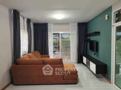 Modern living room with brown sectional sofa and wall-mounted TV, featuring large windows and stylish curtains.