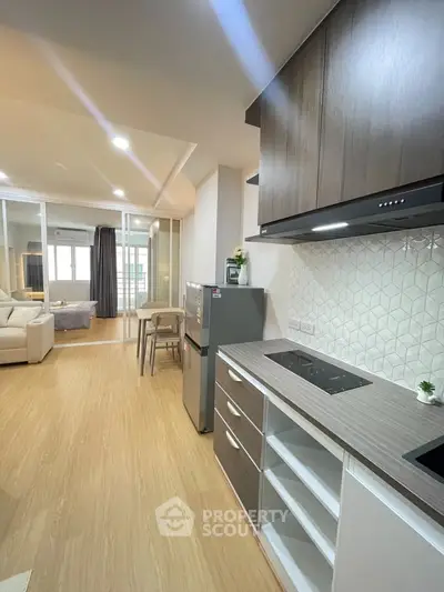 Modern open-layout kitchen with sleek cabinetry and cozy living area in a stylish apartment.