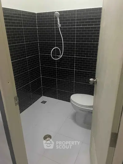 Modern minimalist bathroom with black tiled walls and white fixtures.