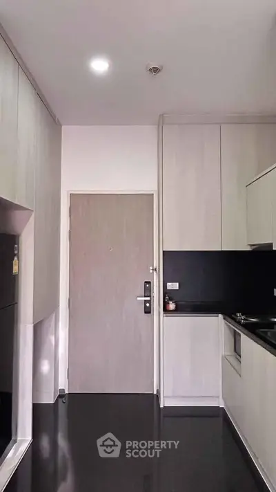 Modern kitchen with sleek cabinetry and black countertops in a contemporary apartment.
