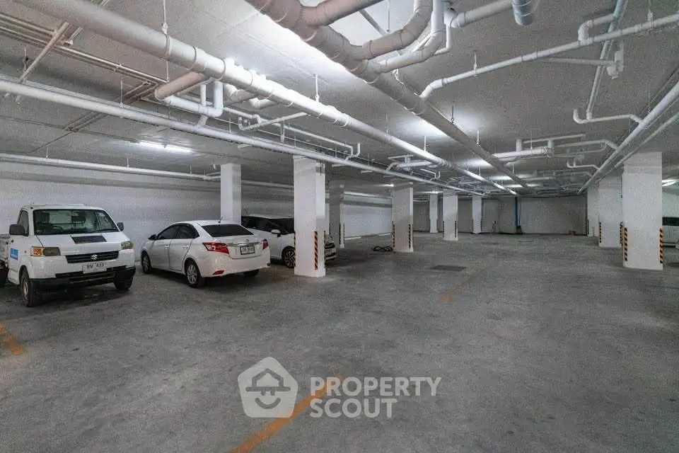 Spacious underground parking area with multiple vehicles and ample lighting.
