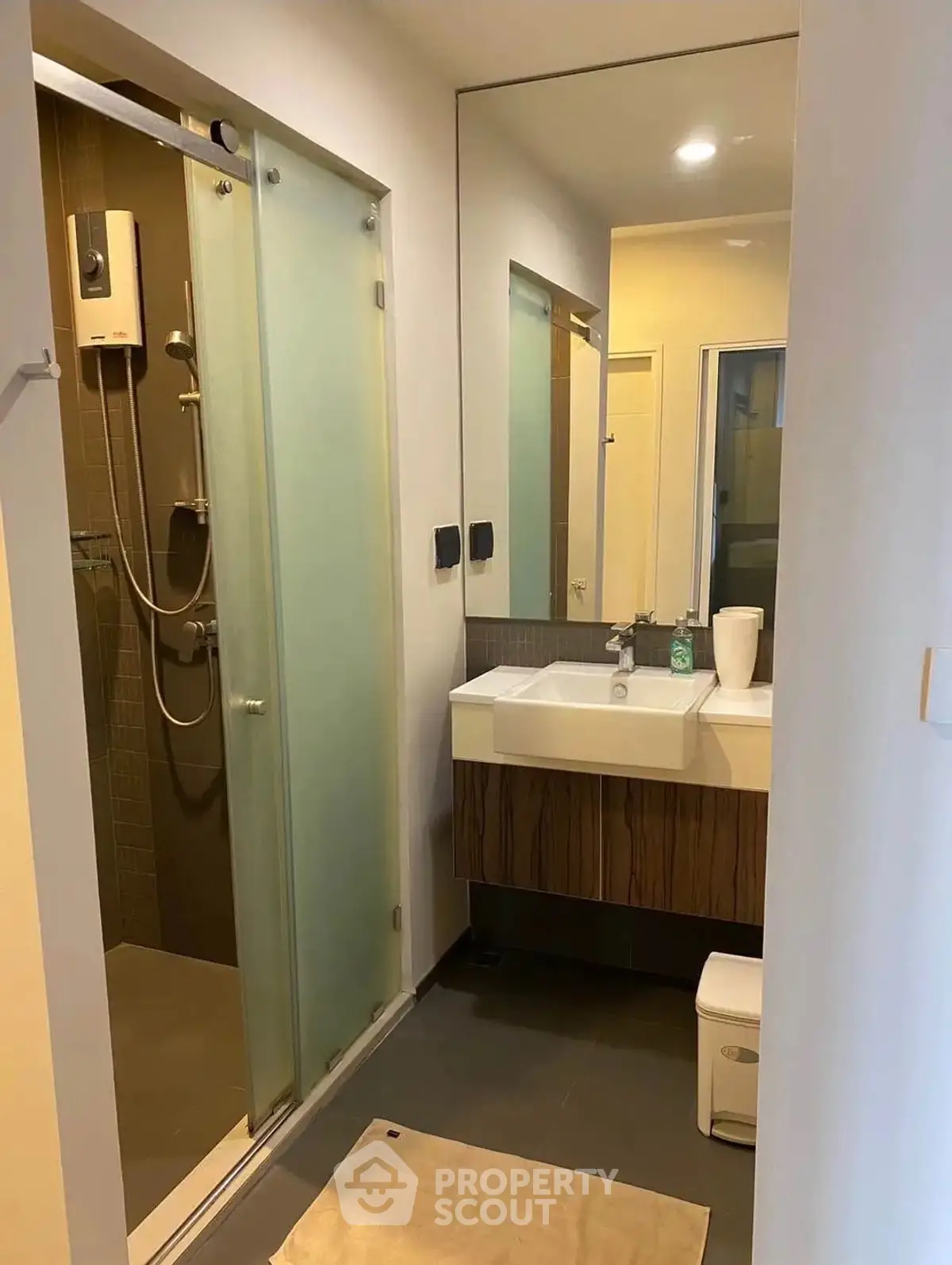 Modern bathroom with glass shower and sleek vanity in contemporary apartment.