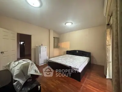 Spacious bedroom with wooden flooring and natural light